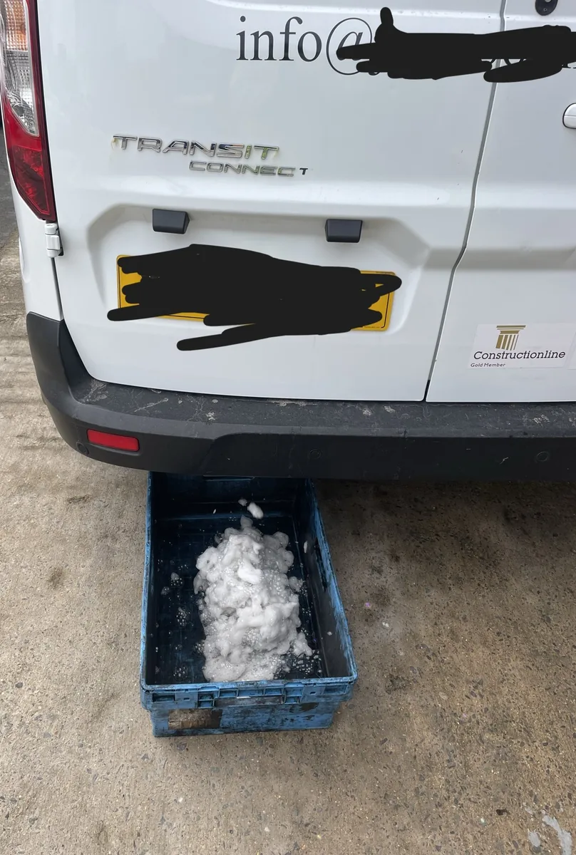 The rear of a white Ford Transit Connect in Stevenage, with foam from the DPF clean collecting in a tray underneath
